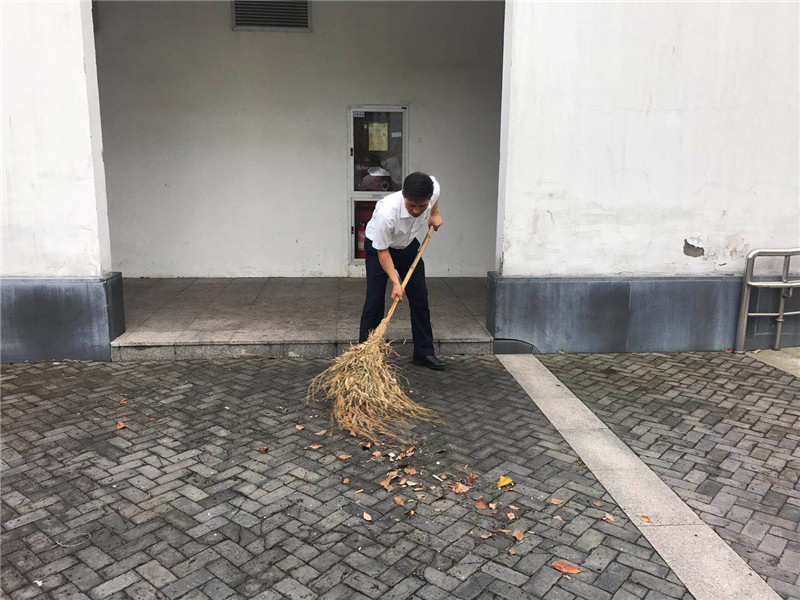 项目主管王世胜在清扫食堂外落叶.jpg